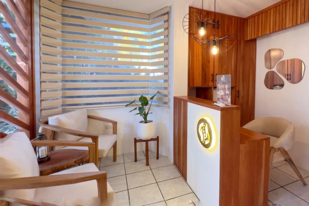 Fotografia, diseño interior de recepción con estética minimalista y natural; mobiliario en madera, detalles orgánicos, iluminación cálida y vegetación integrada